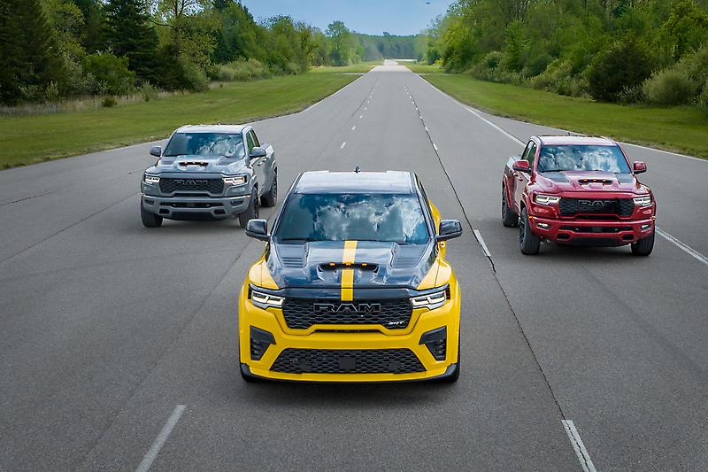 Three Ram 1500 TRX pickup trucks in grey, yellow, and red on a test track.
