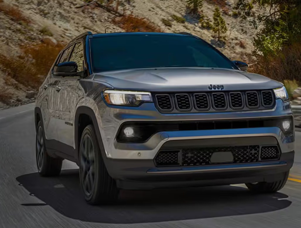 Silver Jeep Compass driving on a winding mountain road.