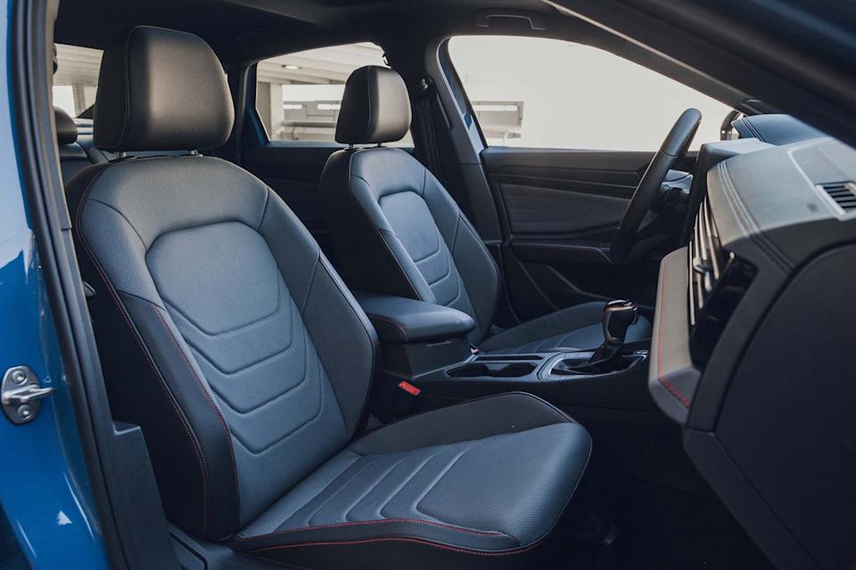 Interior view of a car with leather seats and red stitching.