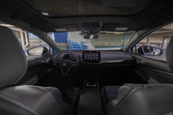 Interior view of a Volkswagen electric vehicle featuring a panoramic sunroof and large touchscreen display.