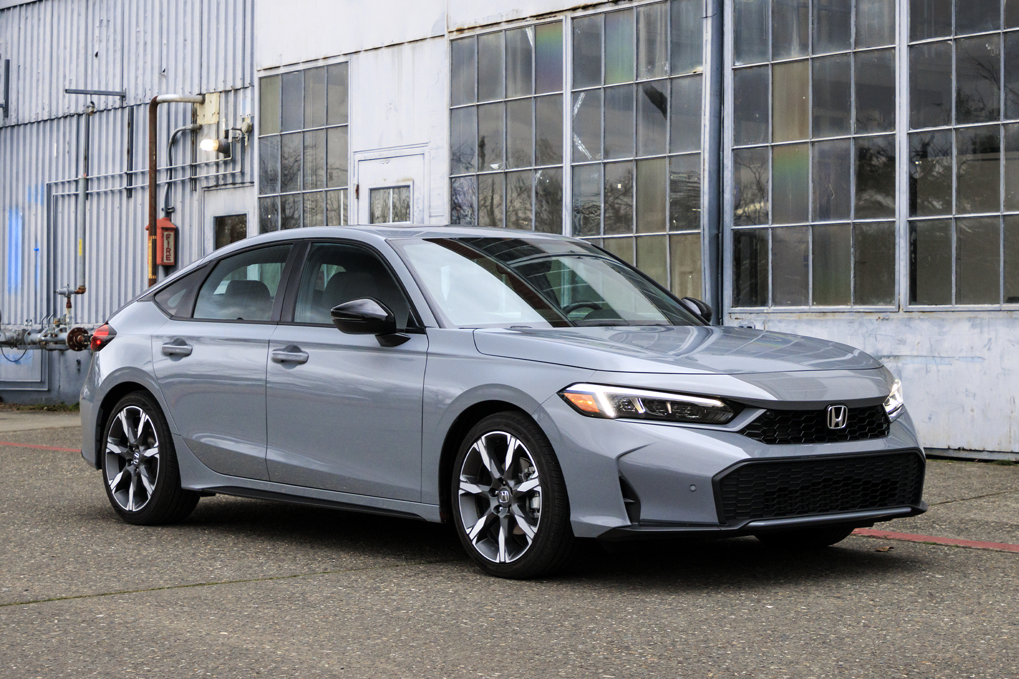 Silver Honda Civic parked in front of an industrial building with large windows.