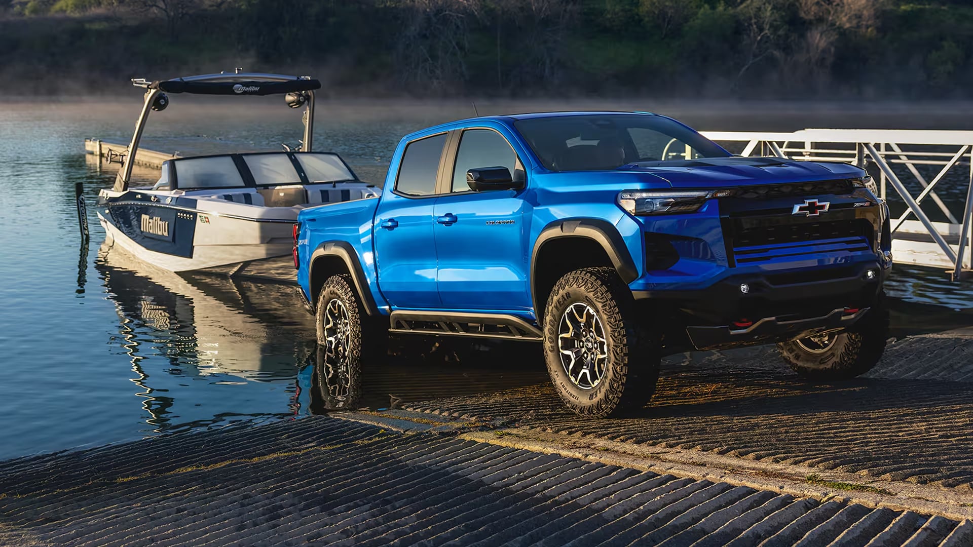 Blue Chevrolet Colorado backing a boat down a launch ramp.