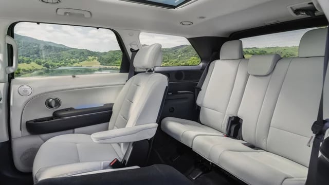 Light gray leather seats inside a spacious SUV looking out at a scenic mountain and lake view.