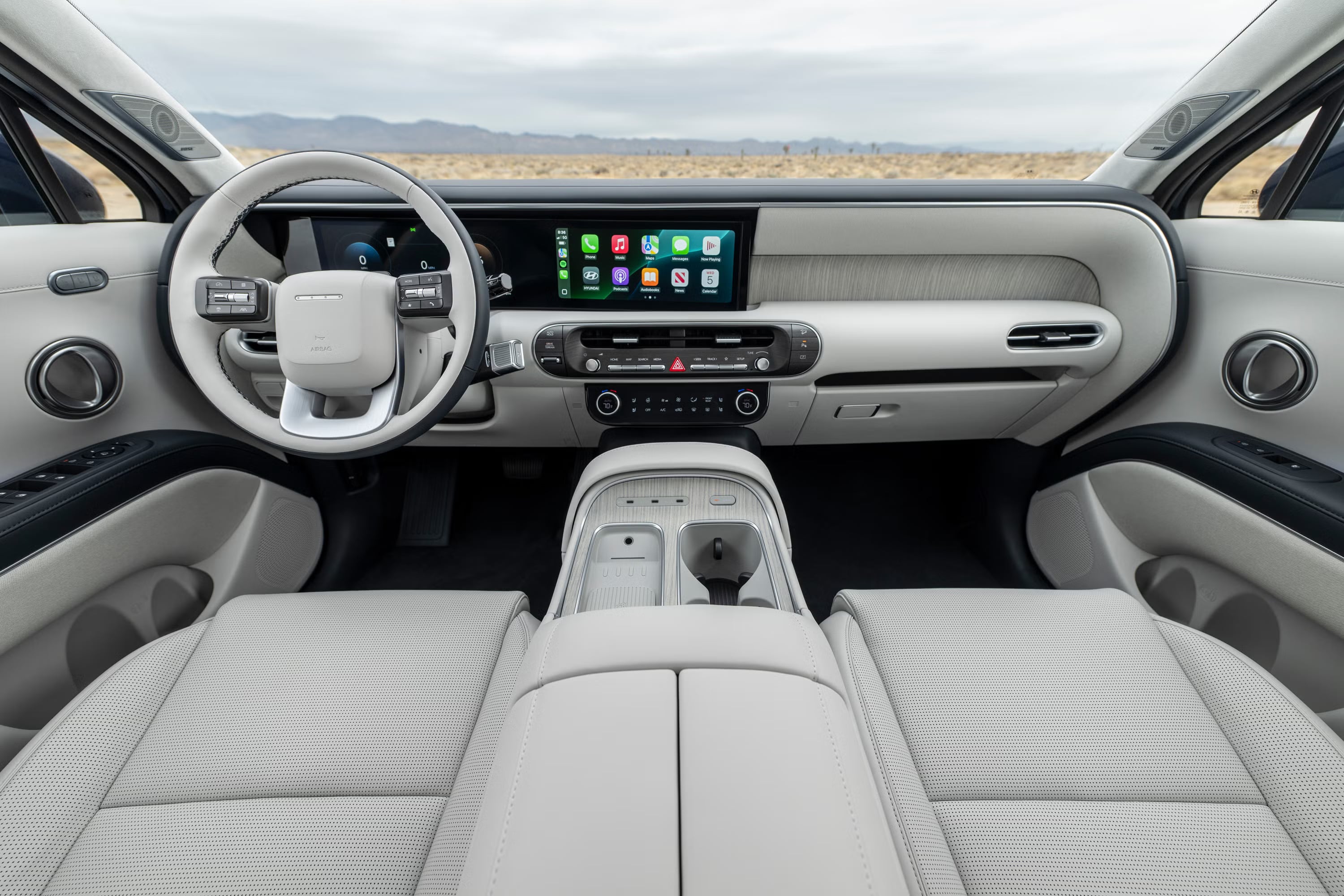 Front interior cabin of a modern SUV with light grey leather seats, dual digital displays, and a white steering wheel.