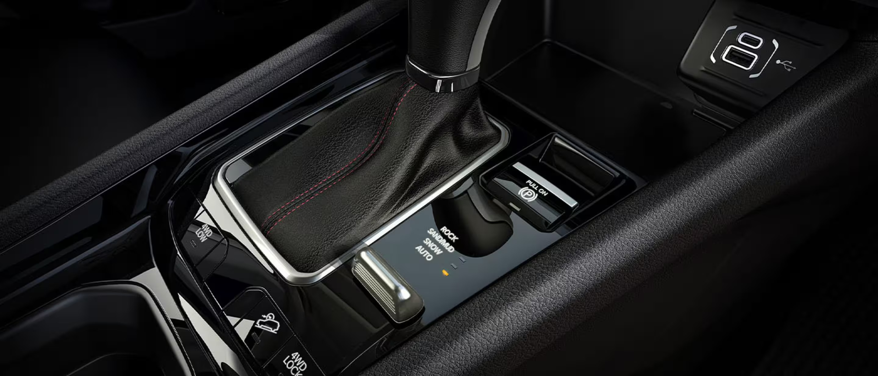 Close-up of a Jeep center console showing the gear shifter, Selec-Terrain drive modes, and electronic parking brake.