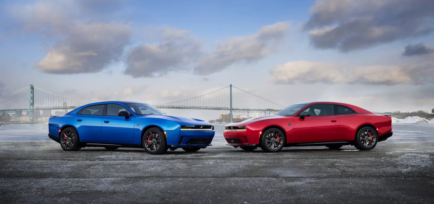 Dodge Charger models parked near a suspension bridge