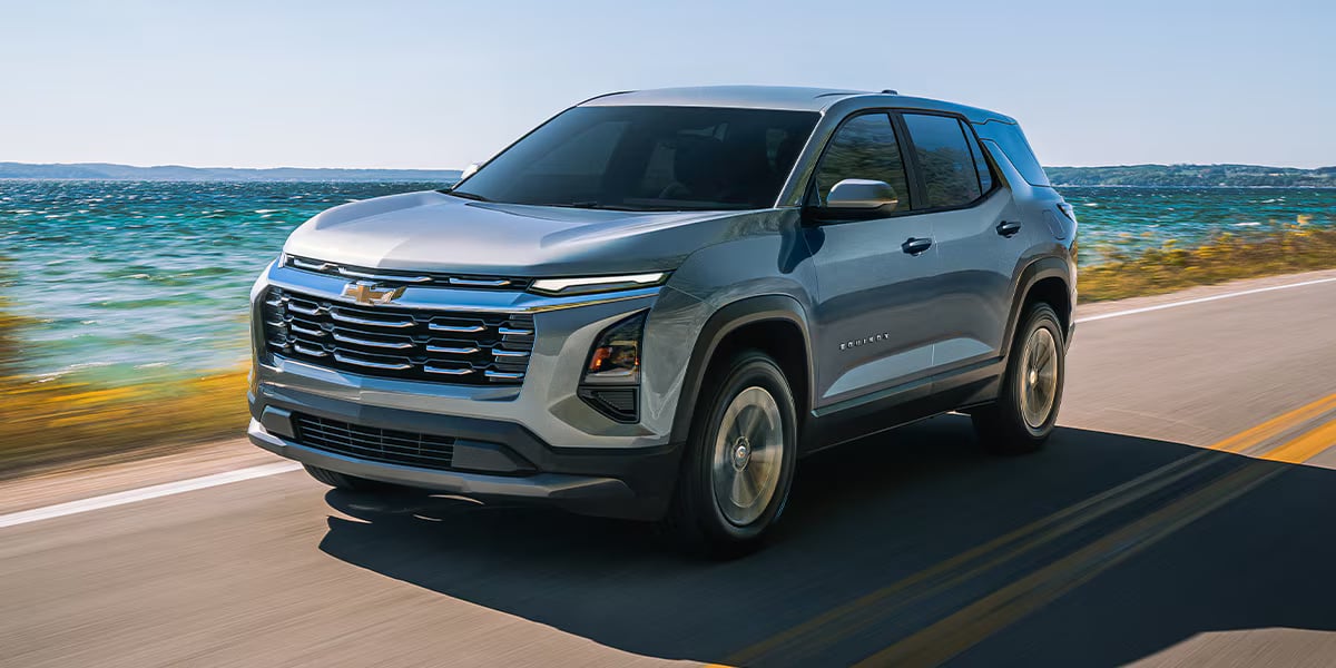 Silver Chevrolet Equinox SUV driving along a scenic coastal road.