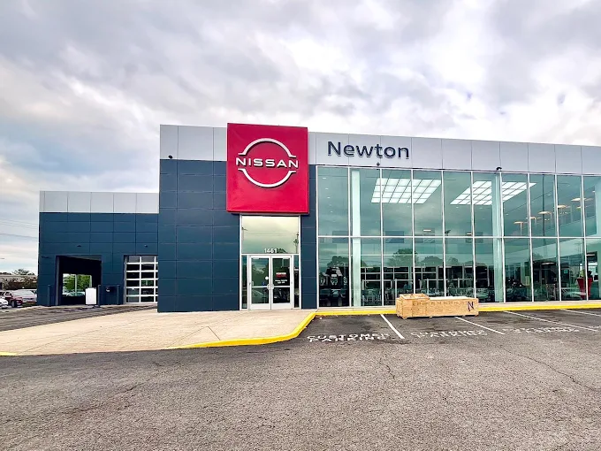 Exterior view of the Newton Nissan of Gallatin dealership with a welcoming entrance and clean showroom windows.