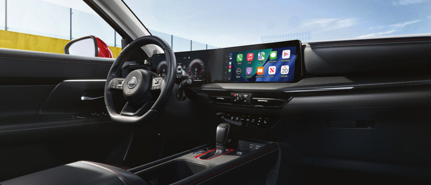 Interior view of a Nissan vehicle featuring a digital dashboard, touchscreen display, and leather-wrapped steering wheel.