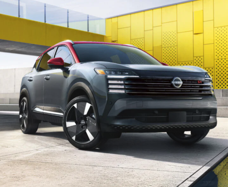 A two-tone Nissan Kicks SR crossover in slate grey and red parked in front of a bright yellow modern building.