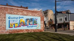 A large 'Greetings from Kane, Pennsylvania' mural painted on a brick building in a downtown area.