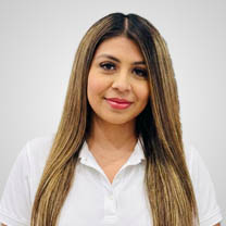 Woman with long highlighted hair smiling in a white polo shirt against a plain background.