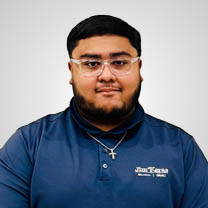 Man with glasses and beard wearing a navy blue polo shirt and cross necklace.