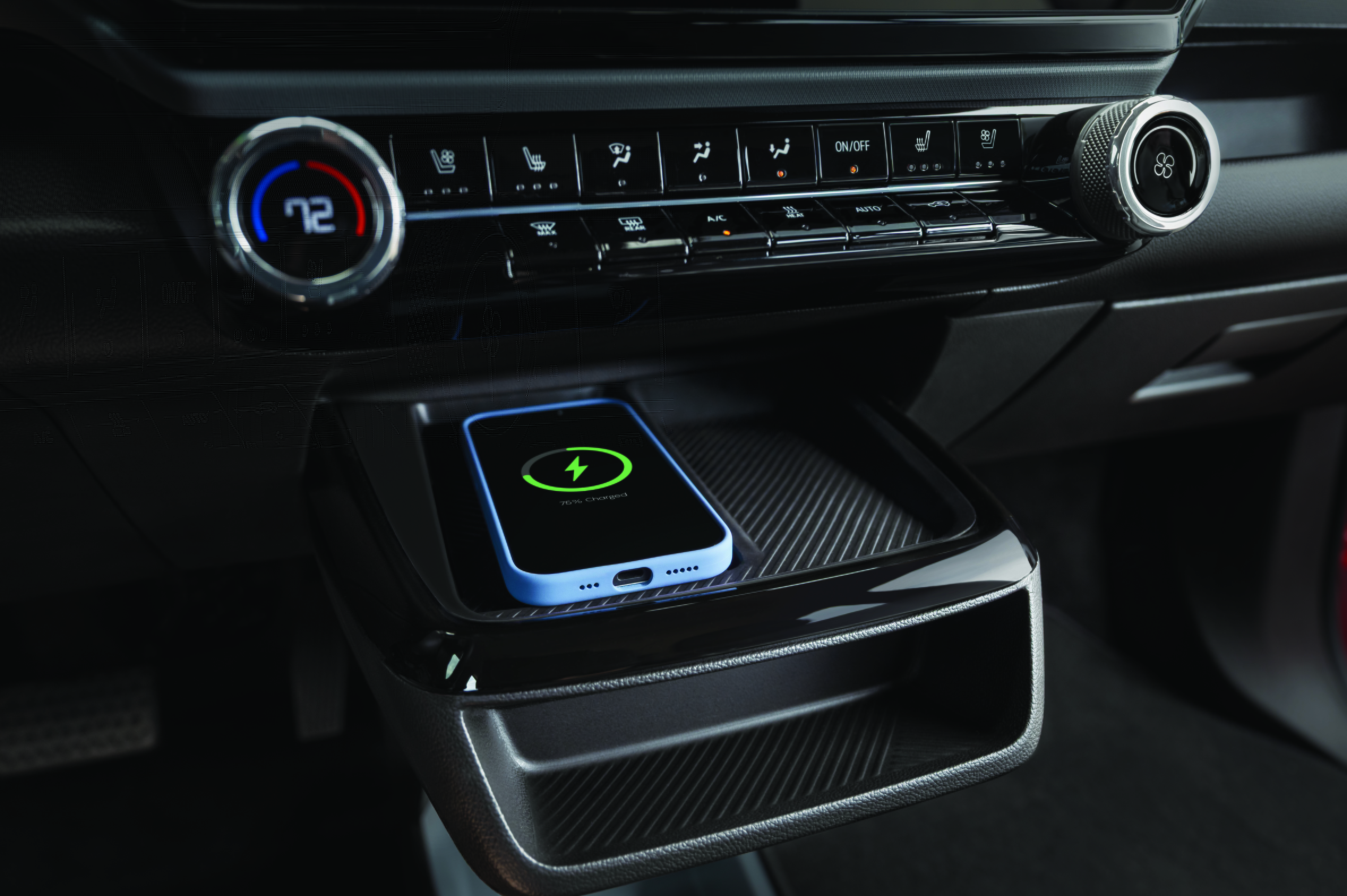 A smartphone in a light blue case charging on a wireless pad in a car's center console.