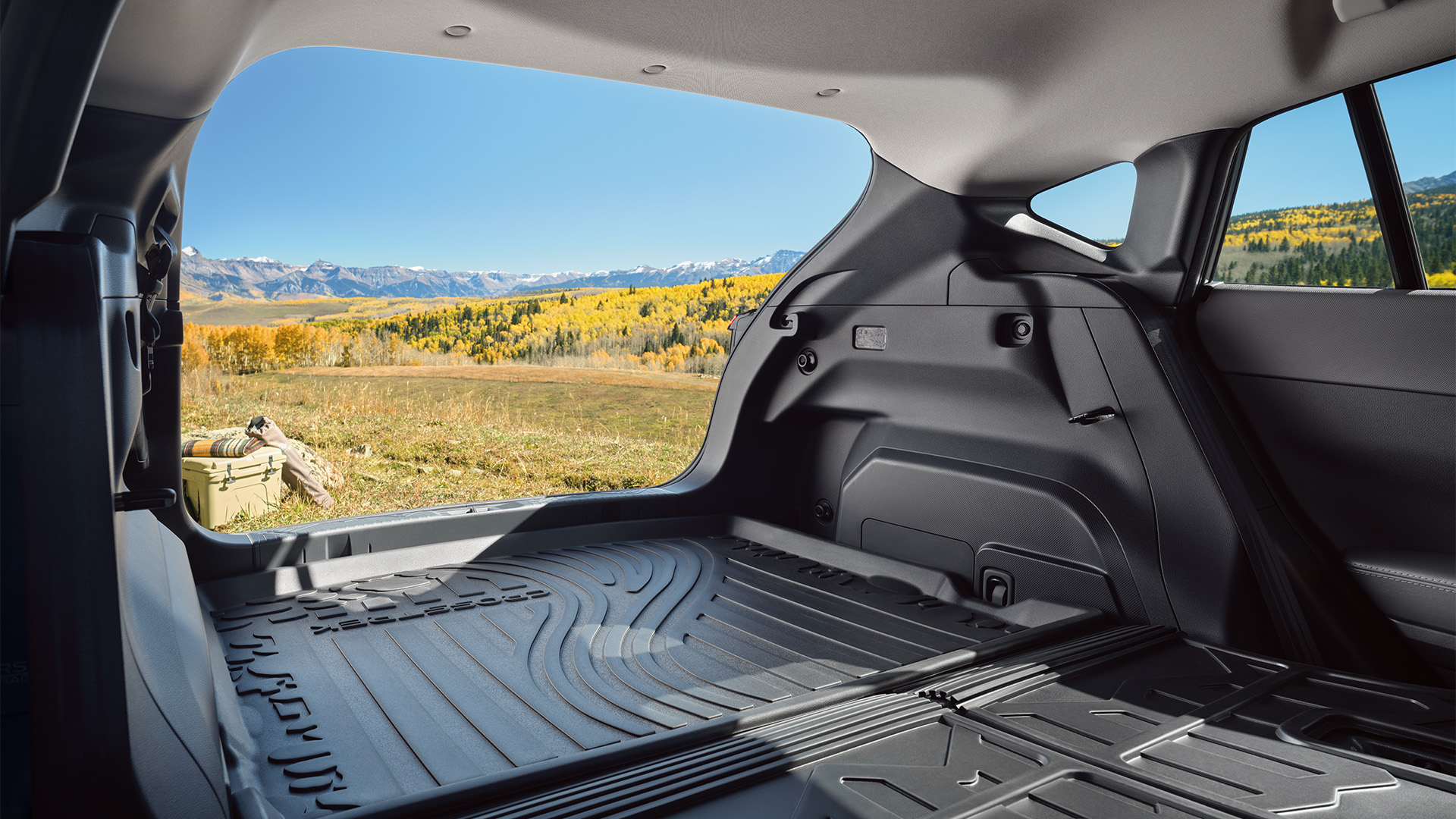 Open trunk of a car with a view of mountains and golden trees.