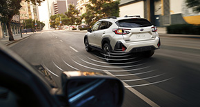 White Subaru car with simulated sensors for safe driving on city street.