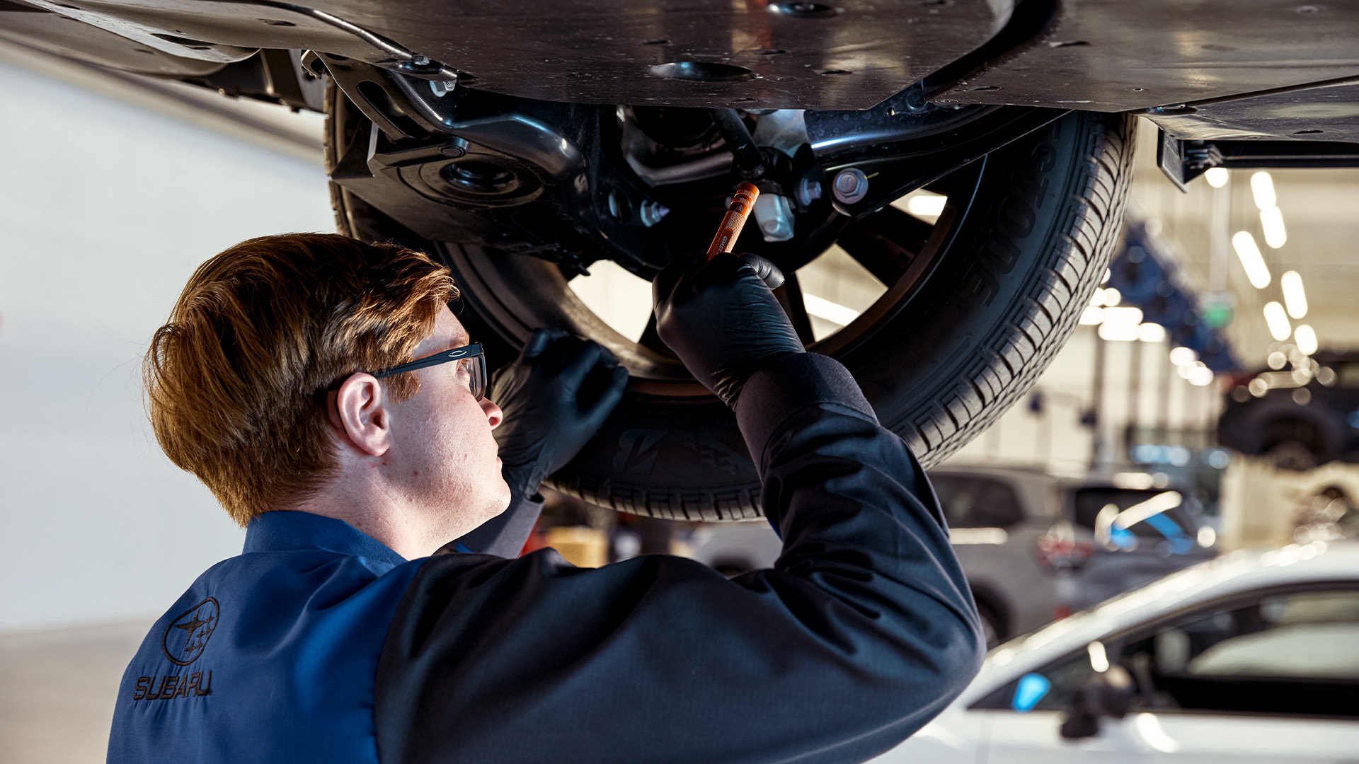 A technician mounting a tire onto a Subaru alloy wheel.