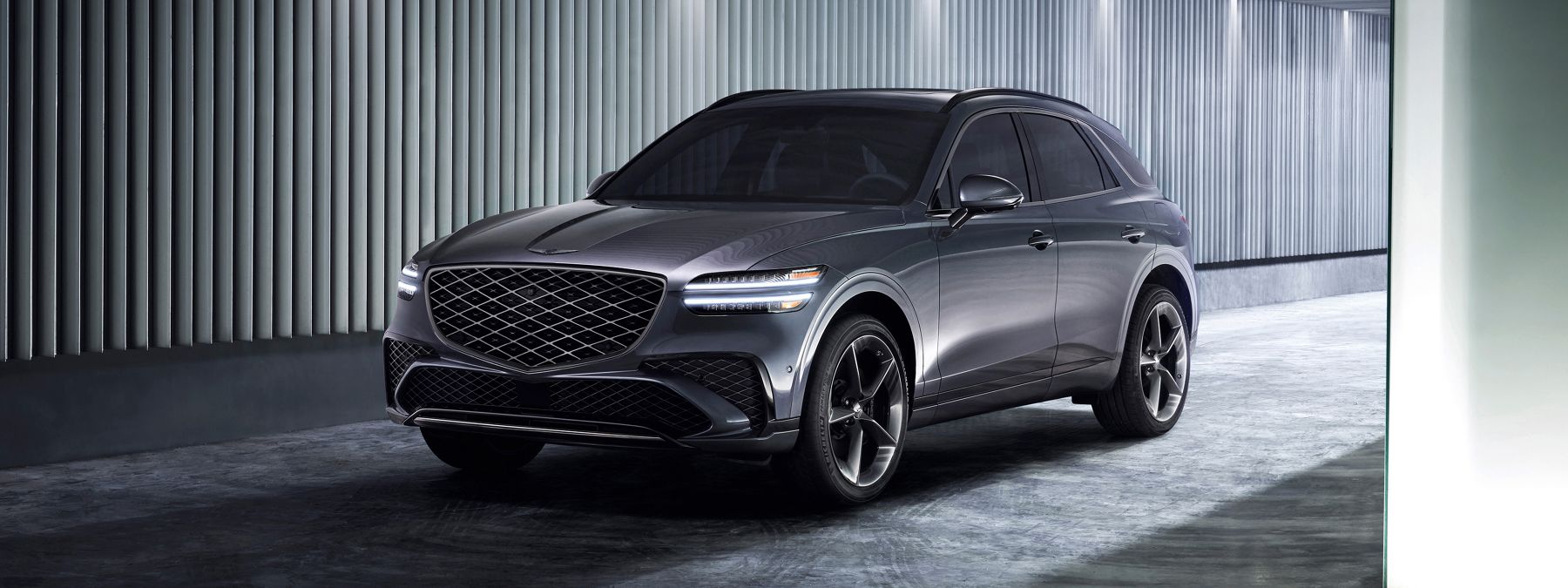 Sleek gray Genesis GV70 luxury SUV parked in a modern minimalist garage with vertical slat walls.