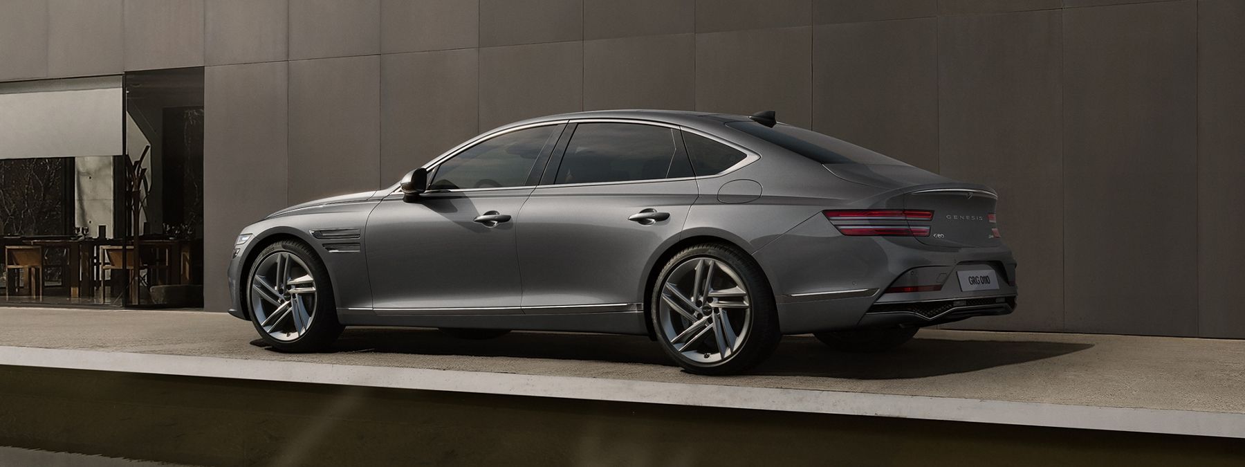 Gray Genesis G80 luxury sedan parked on a clean, modern patio.