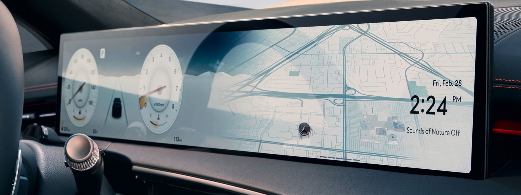 A wide curved digital dashboard in a modern vehicle displaying gauges and navigation.