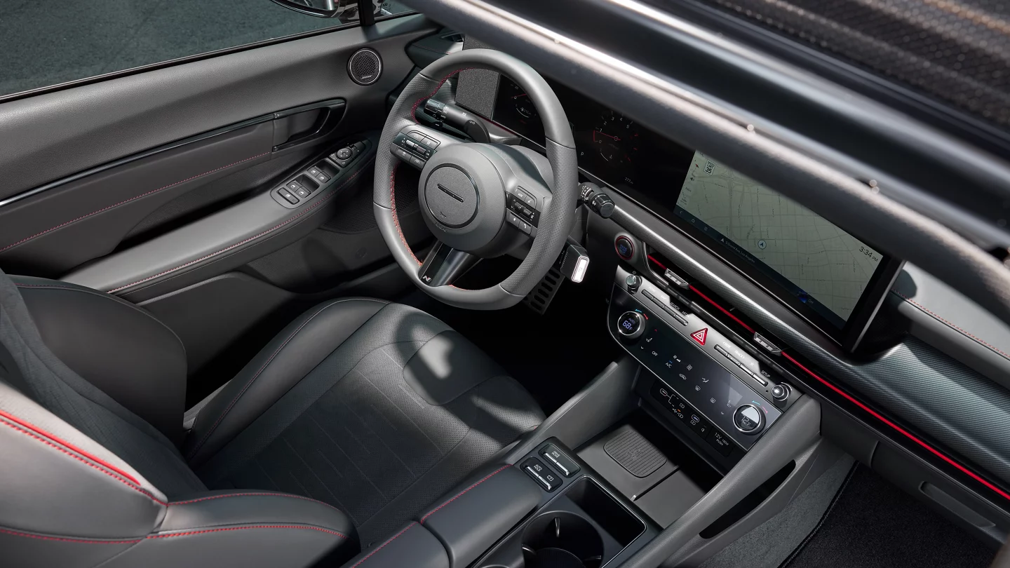Interior view of a modern Hyundai Sonata cockpit with grey seats, red stitching, and a large digital dashboard.