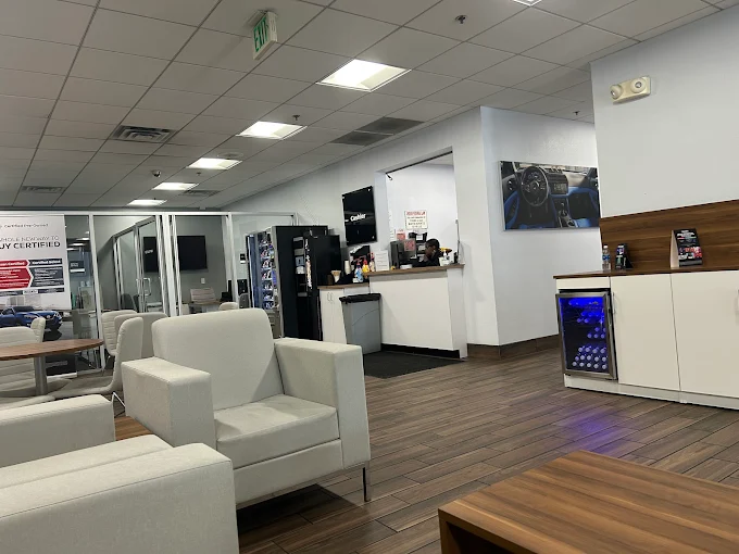 A modern car dealership waiting area with white chairs.