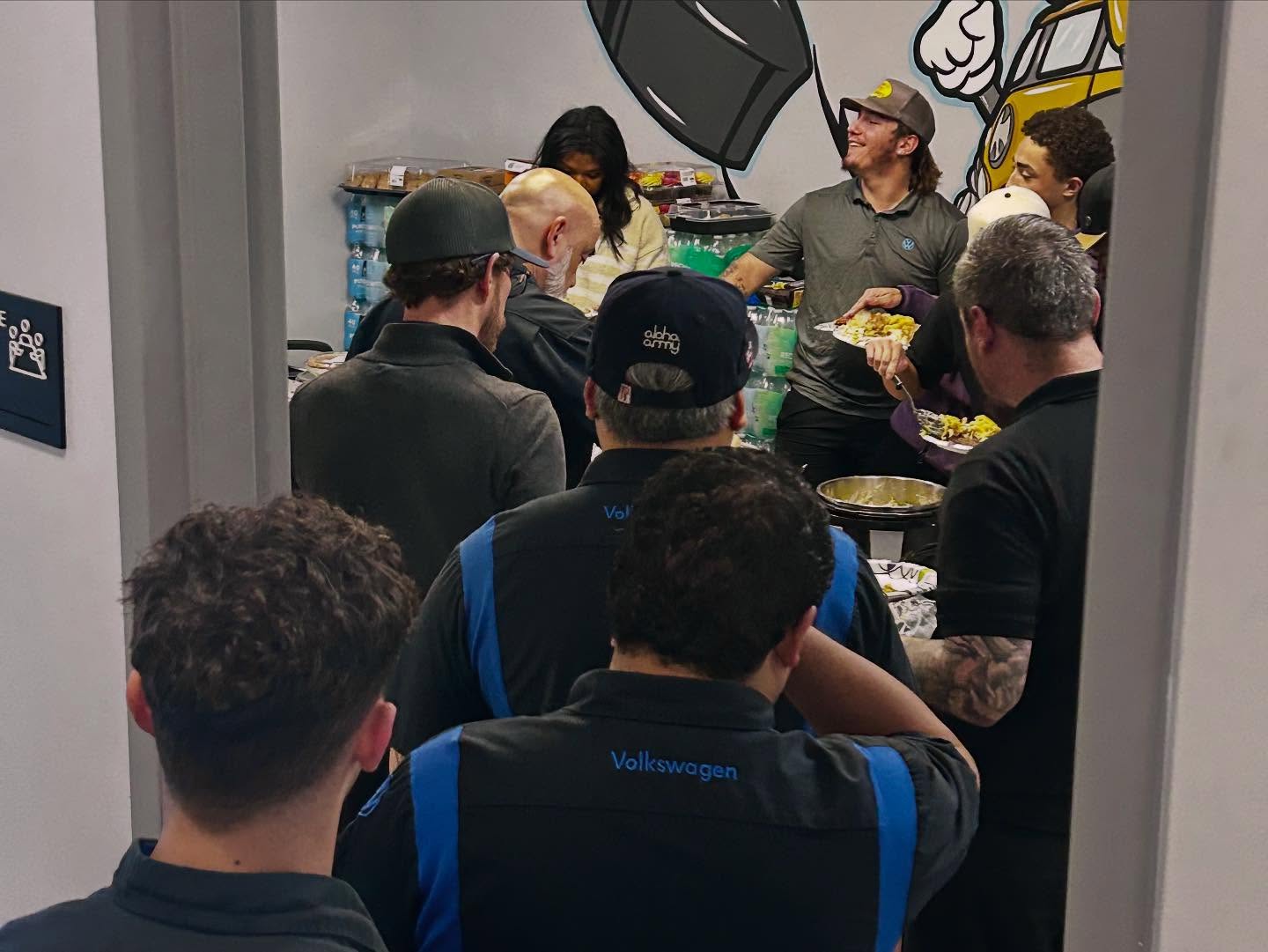 People stand in line at a buffet with food.
