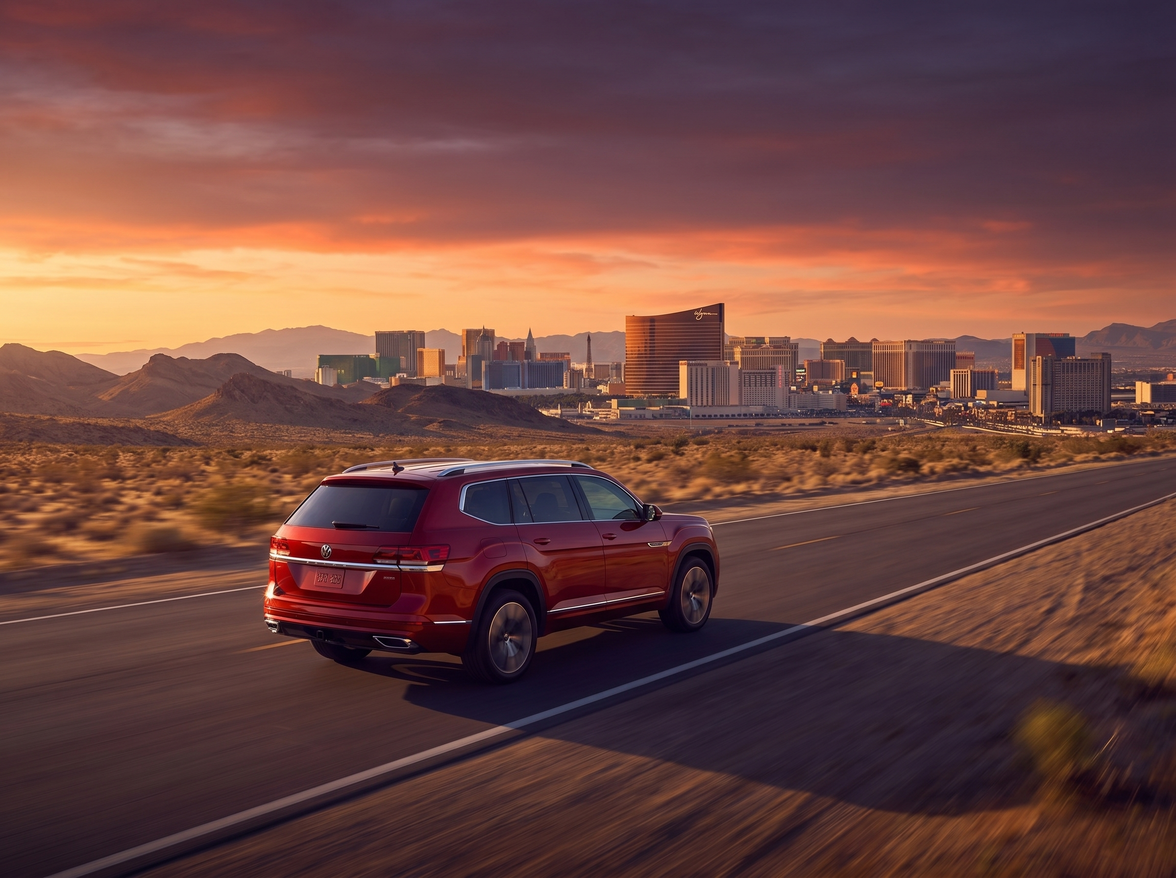 Red Volkswagen SUV driving on a desert highway toward the Las Vegas skyline at sunset.