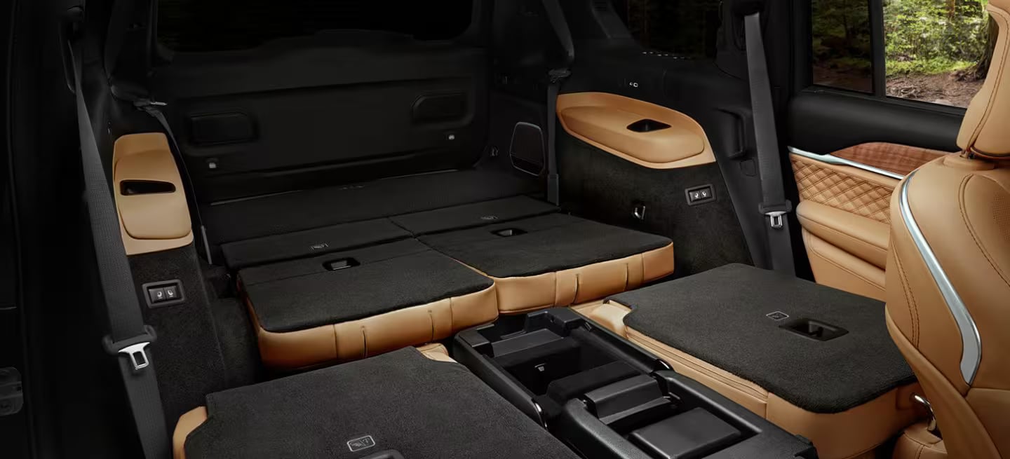 Cargo area of an SUV with the second and third-row seats folded flat, showing tan leather trim.