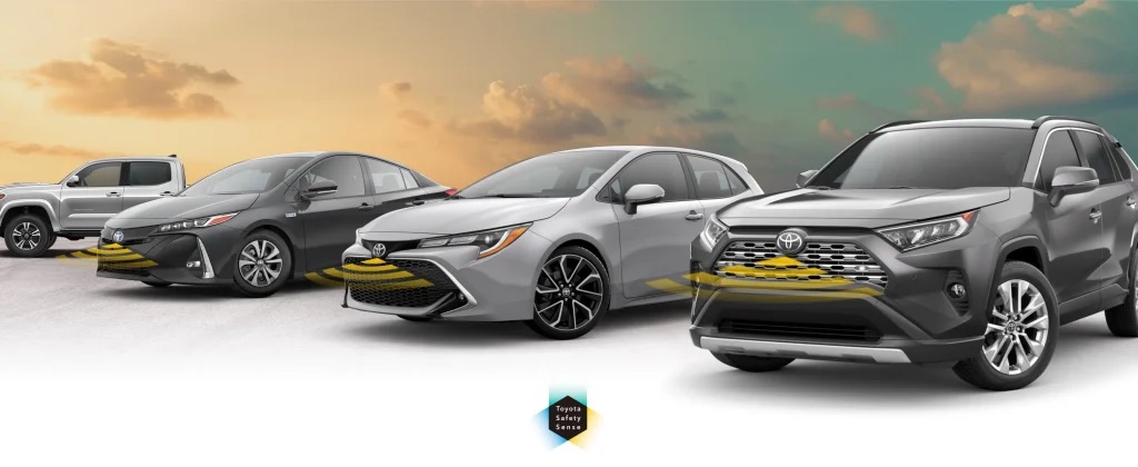 Lineup of four Toyota vehicles showing radar sensor beams from their front grilles against a sunset sky.