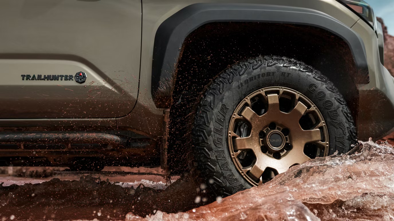 Toyota Tacoma truck wheel splashing through mud.
