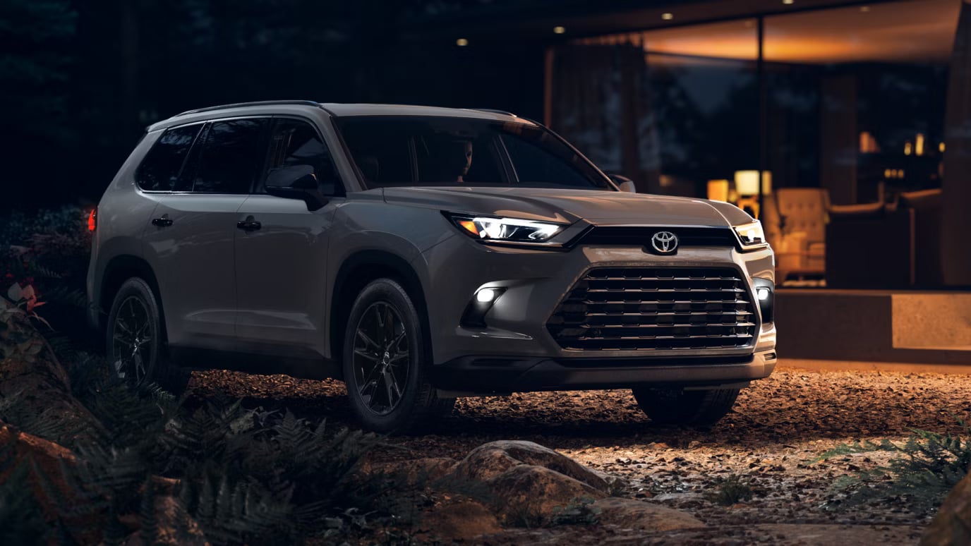 Silver Toyota Grand Highlander parked on a gravel path at dusk in front of a modern home.