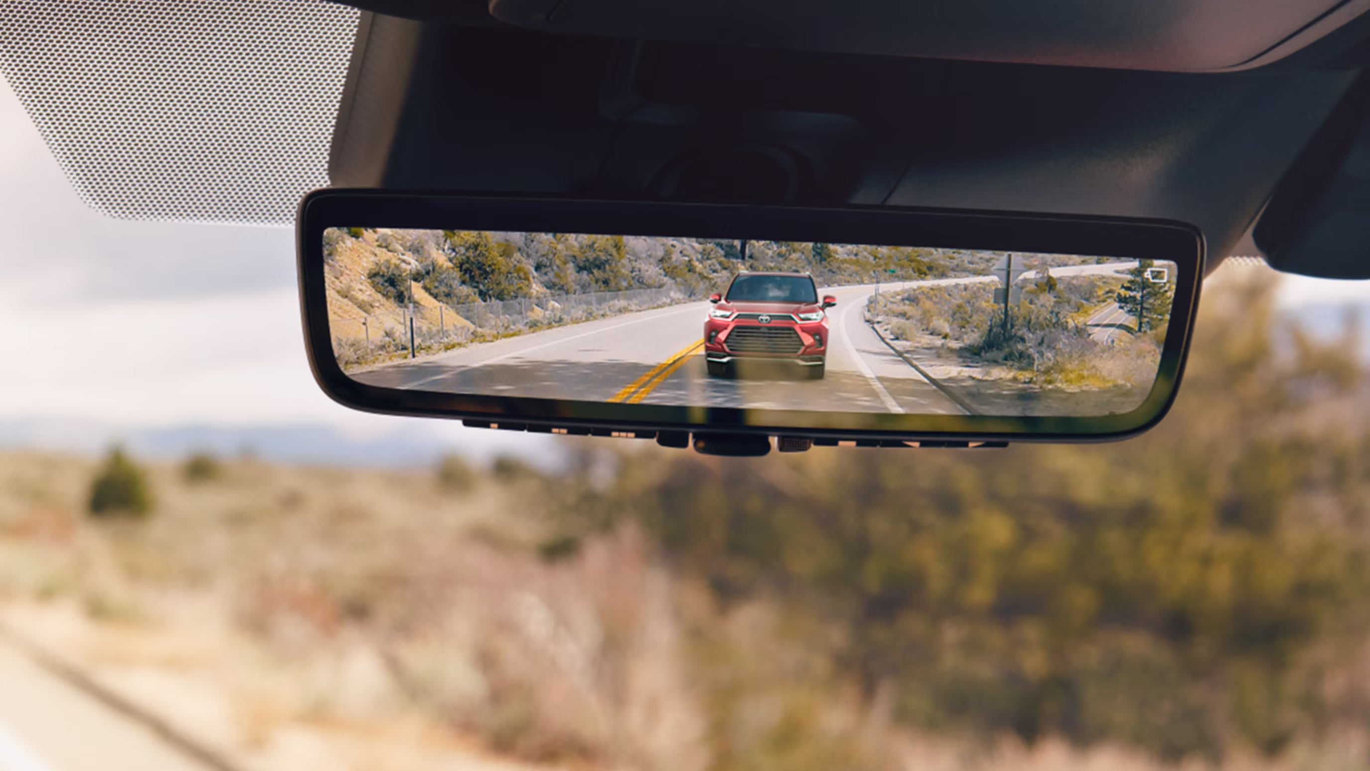 Digital rearview mirror displaying a red Toyota SUV driving behind the vehicle.