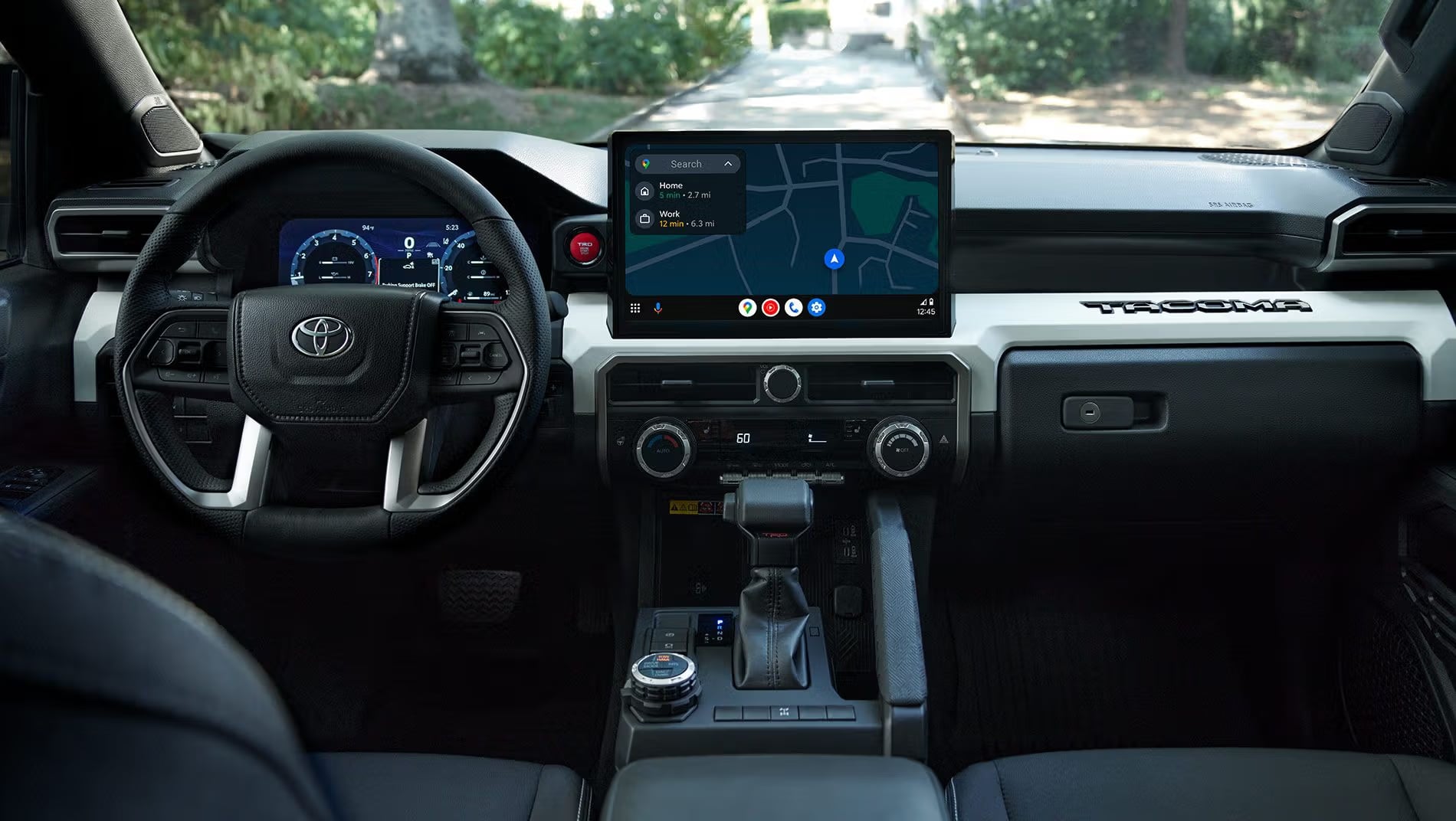 Dashboard interior of a Toyota Tacoma showing a large touchscreen display, leather steering wheel, and digital gauges.