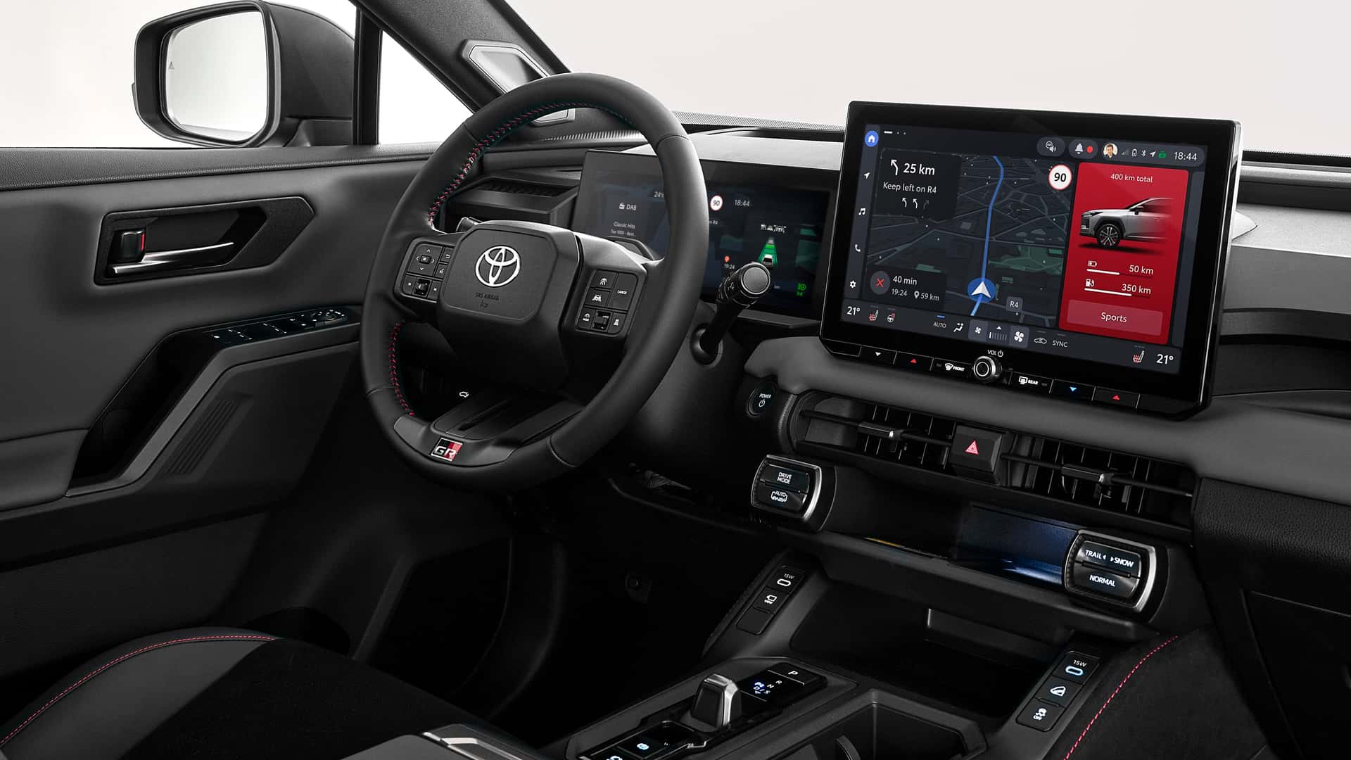 Modern Toyota interior featuring a black leather steering wheel, digital instrument cluster, and large touchscreen display.