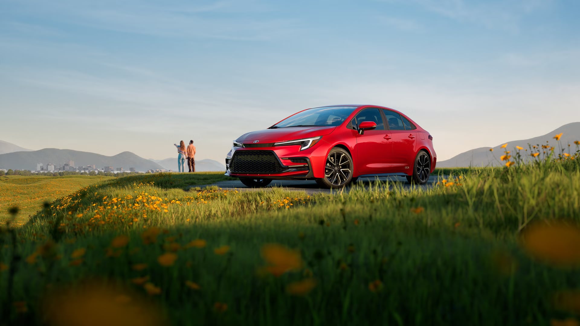 Red Toyota Corolla parked outdoors near a grassy hillside