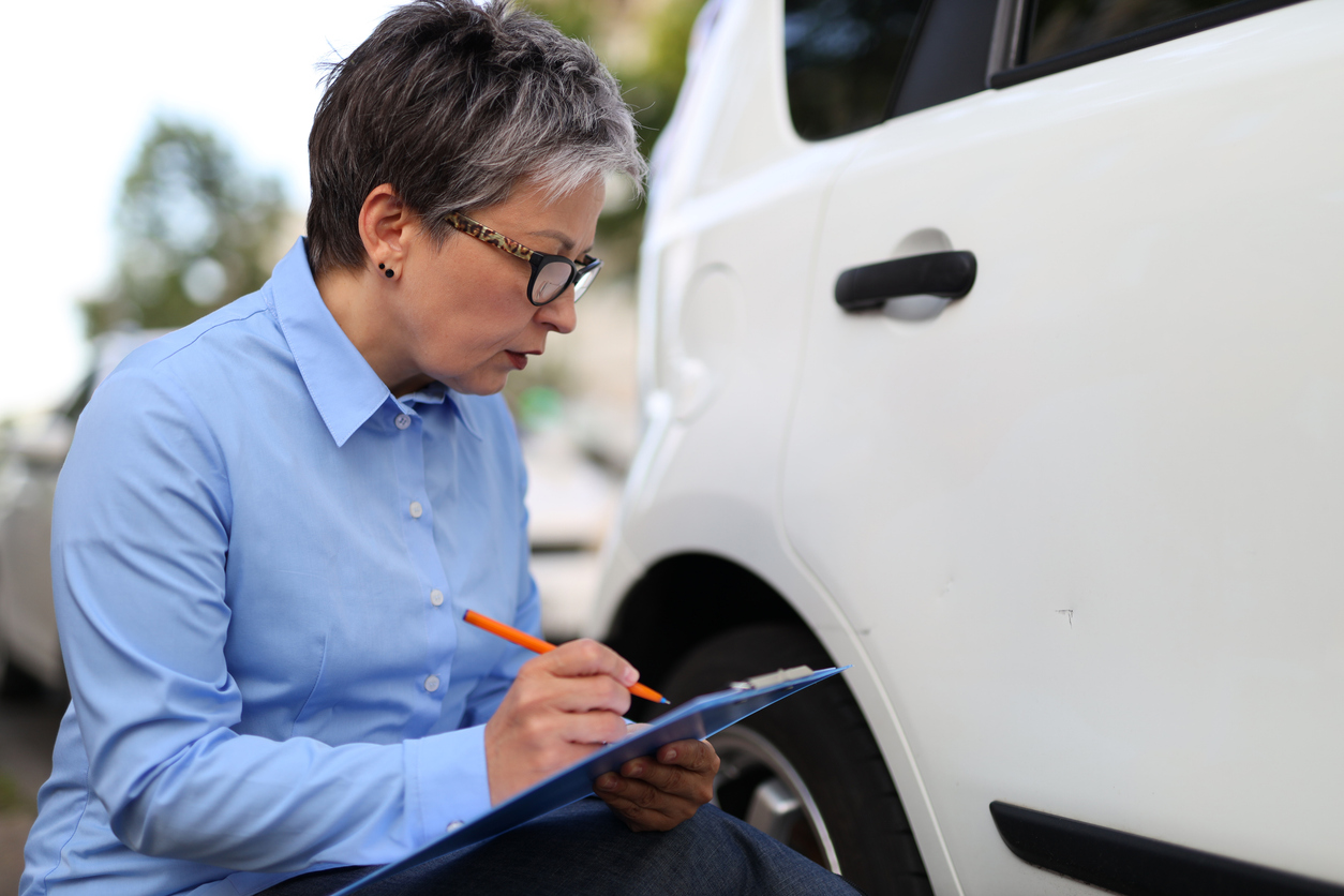 Dealership employee valuating a vehicle while writing on a clipboard.