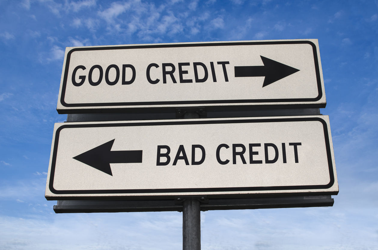 Two directional signs on a post against a blue sky, one pointing right for 'GOOD CREDIT' and one left for 'BAD CREDIT'.